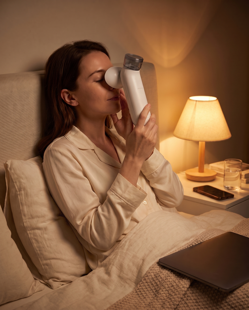 Woman winding down in bed using the Eye Mist Spa